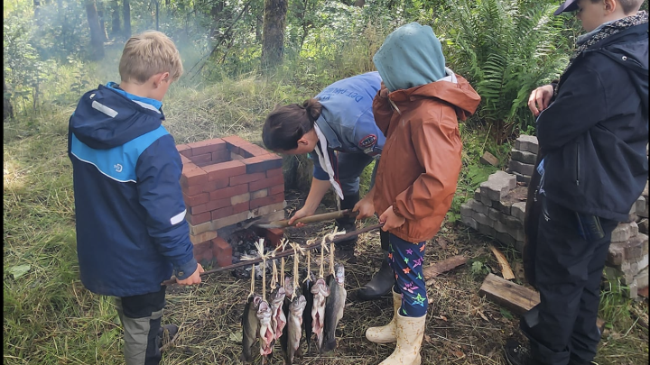 Børn og leder med fisk der skal ryges